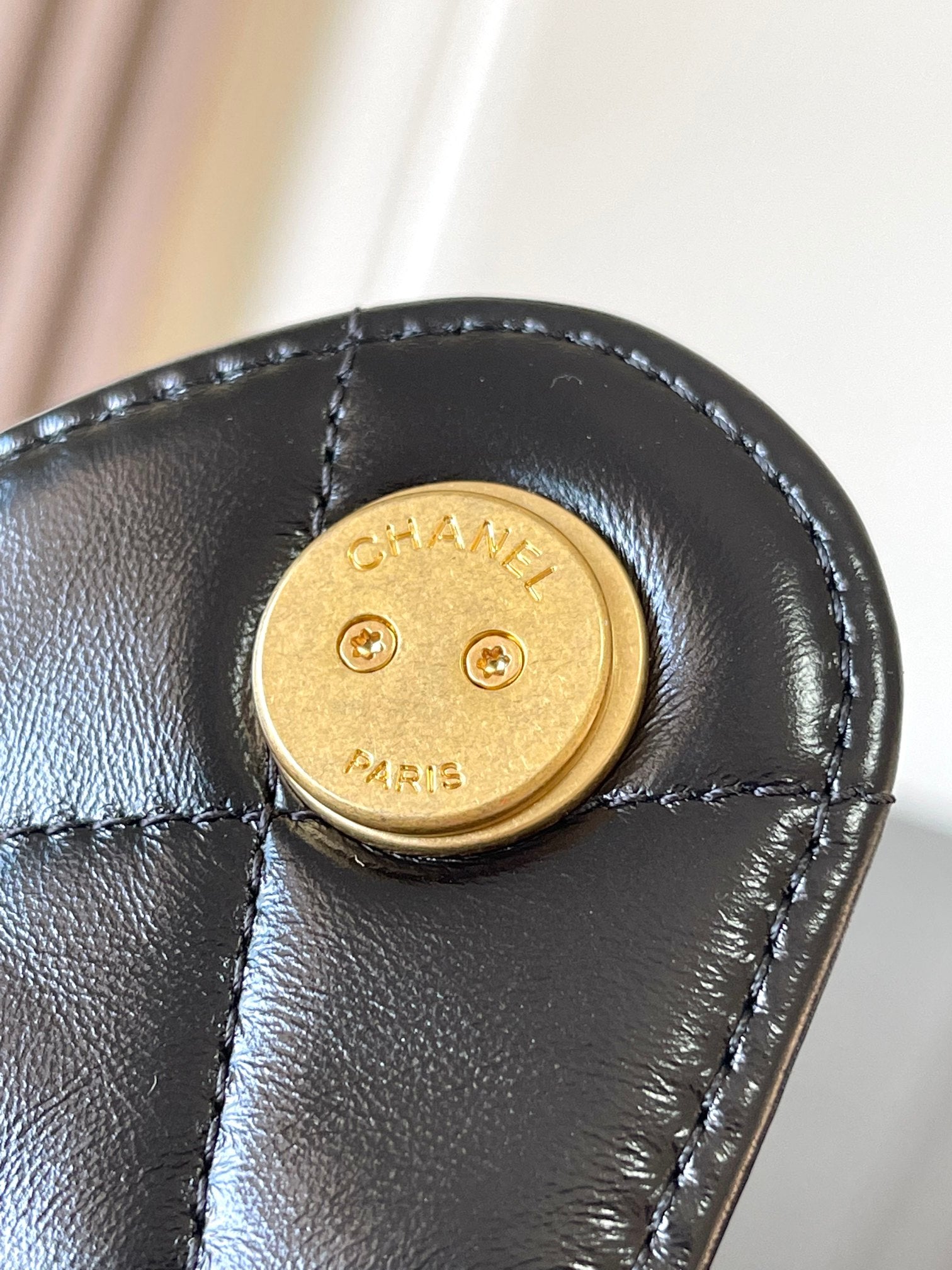 Chanel gold snap-button clasp on black leather flap bag