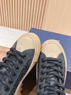 Black low-top sneakers close-up on blue box, showing textured side panels