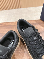 Black low-top sneakers close-up, tongue and lace area visible with beige sole