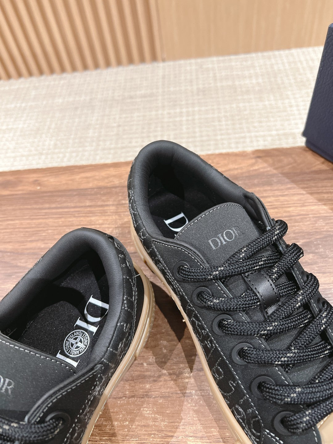 Black low-top sneakers close-up, tongue and lace area visible with beige sole