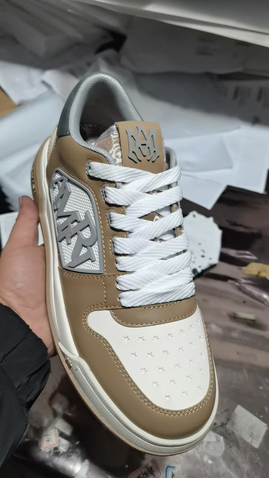 Tan and white sneakers with white laces and patterned side logo patch