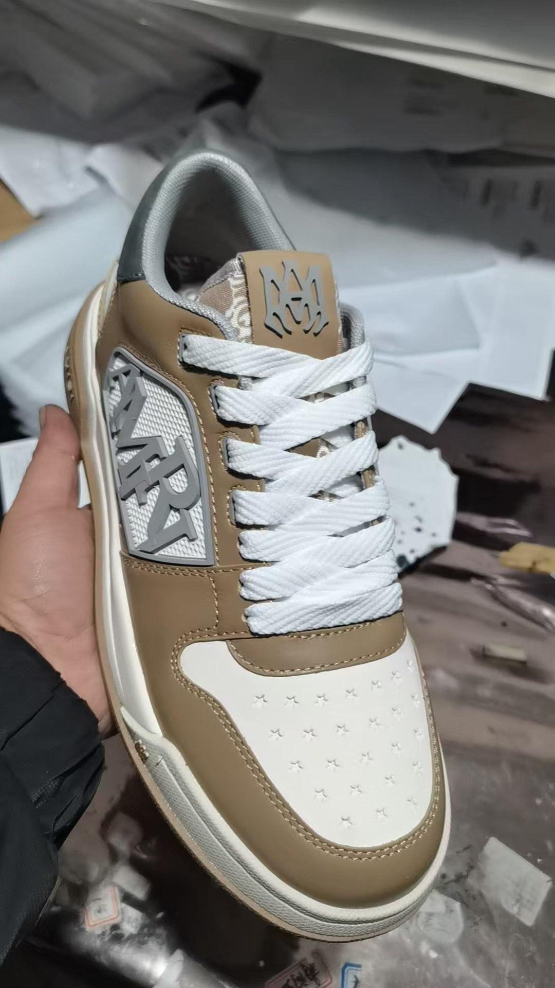 Tan and white sneakers with white laces and patterned side logo patch