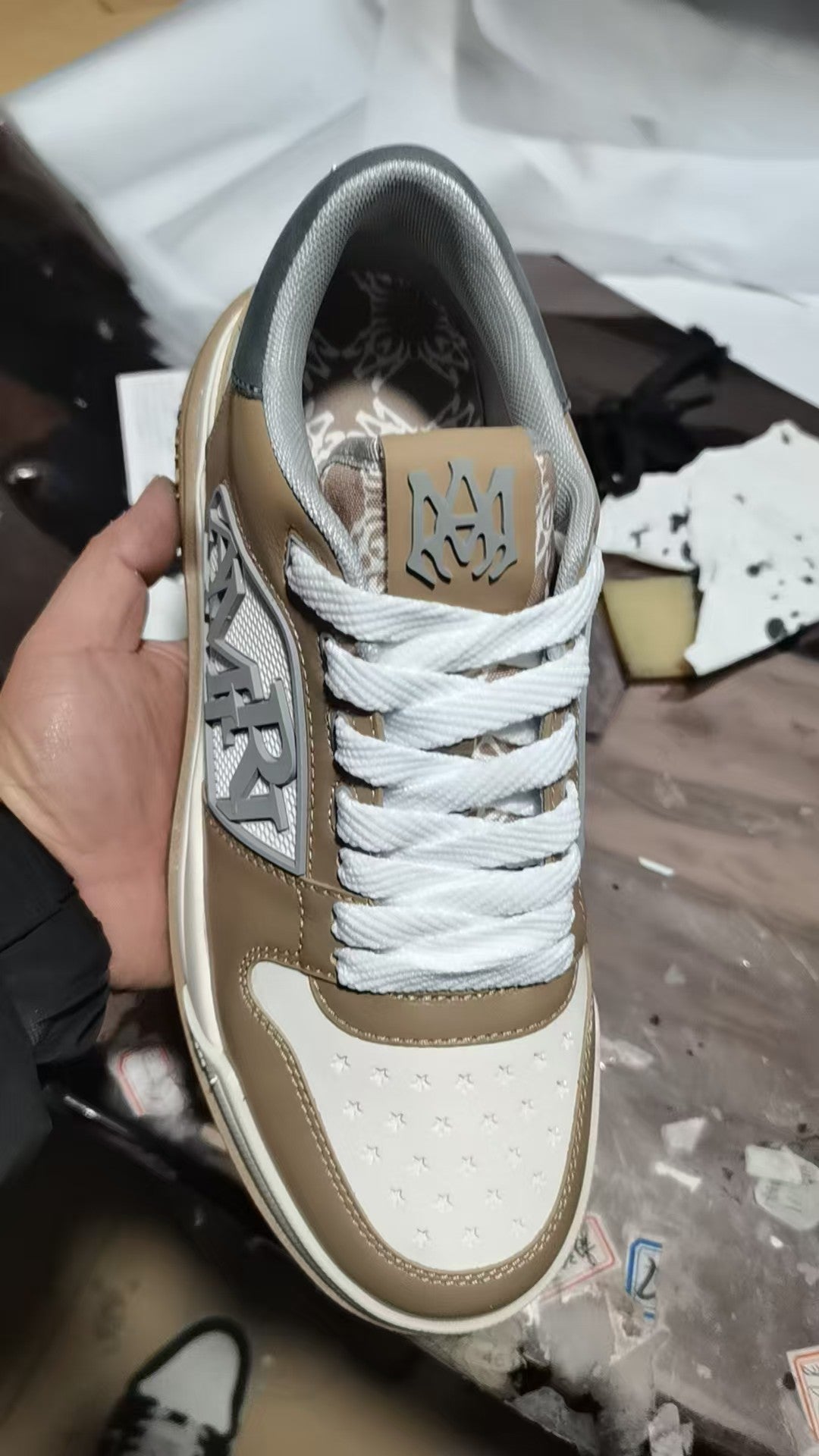 Tan and white sneakers with white laces and logo detail on the tongue