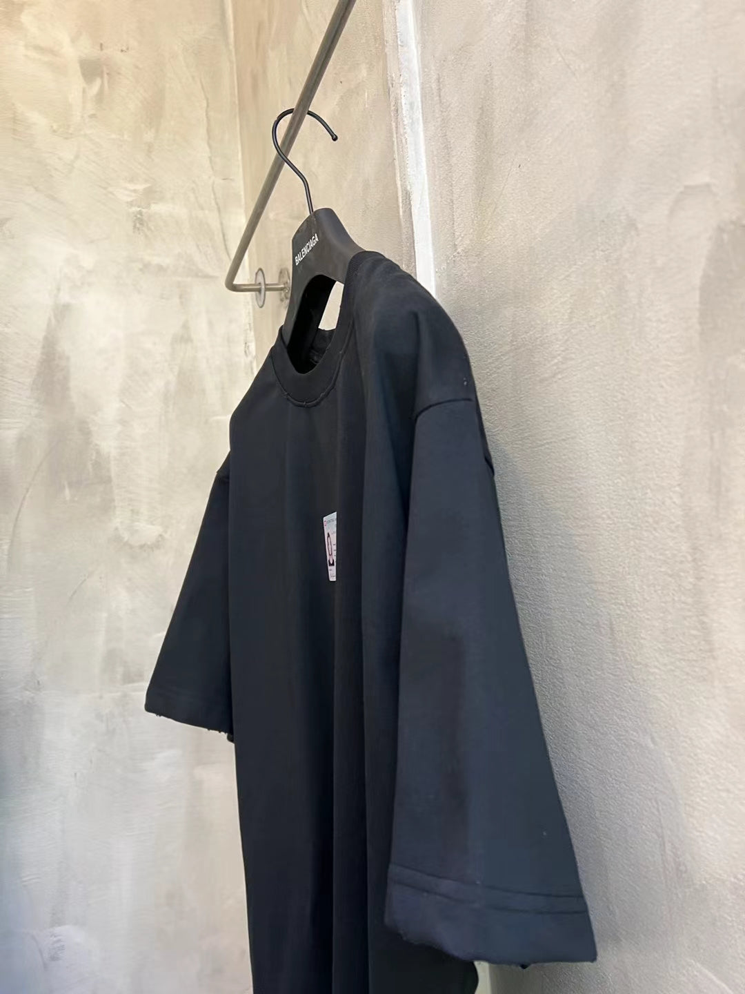 Dark short-sleeve T-shirt on hanger, side view
