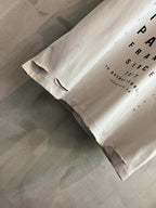 White T-shirt hem close-up with black text print and distressed raw edges
