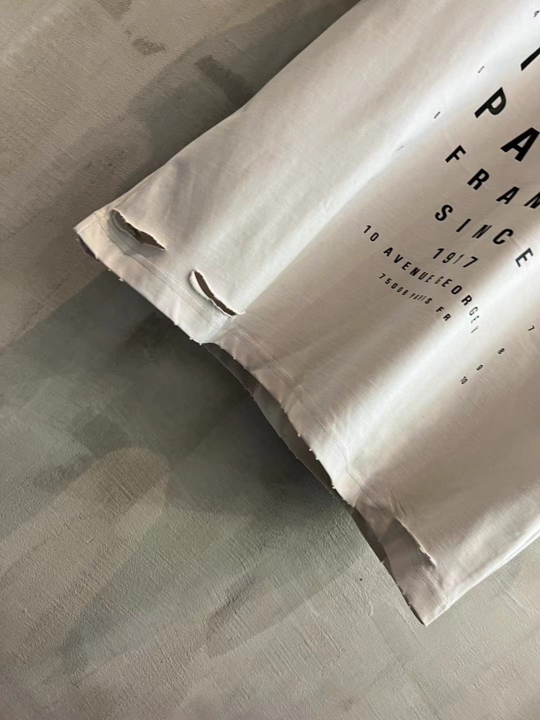 White T-shirt hem close-up with black text print and distressed raw edges