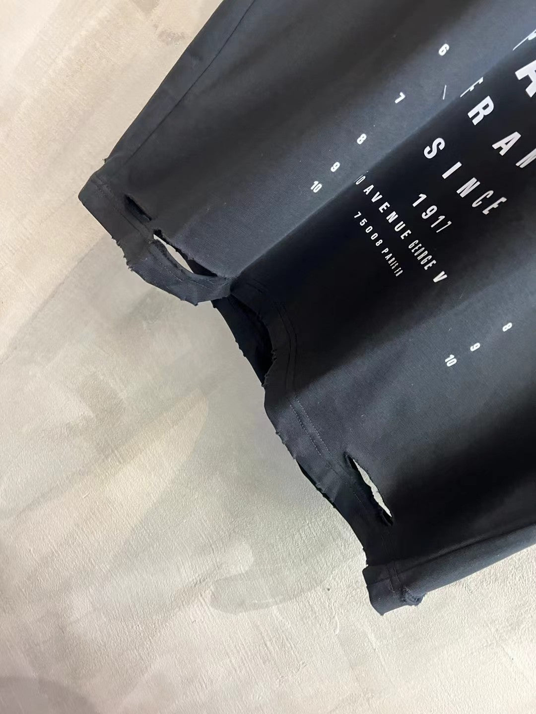 Balenciaga black T-shirt hem detail with distressed tears and frayed edges