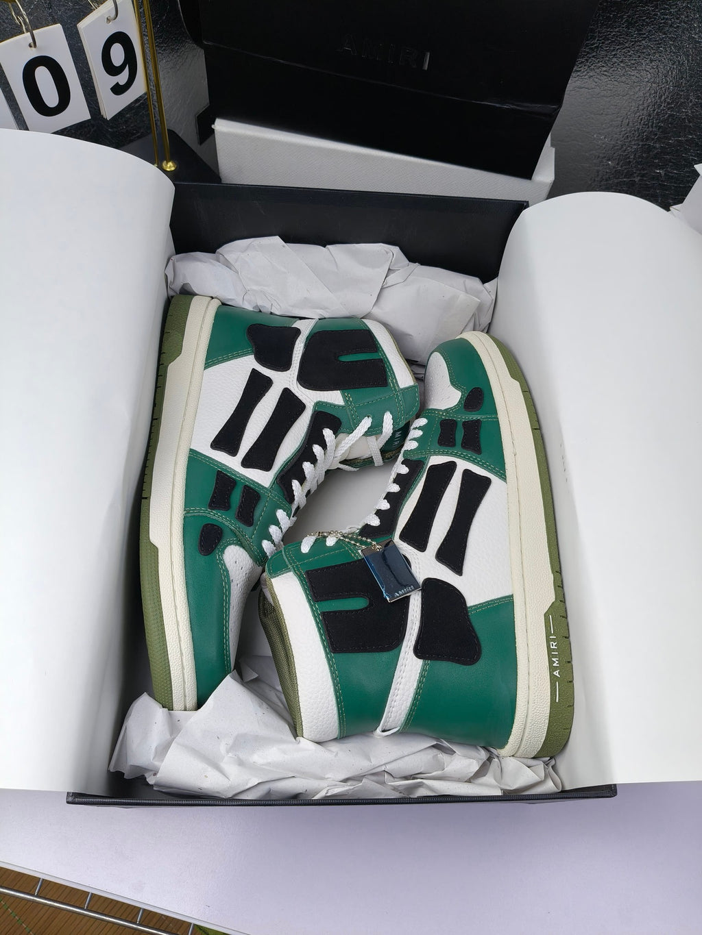 Green and white high-top lace-up sneakers with black patchwork and cream midsoles.