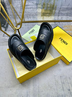 Fendi black slide sandals on yellow box, gold logo buckle on strap