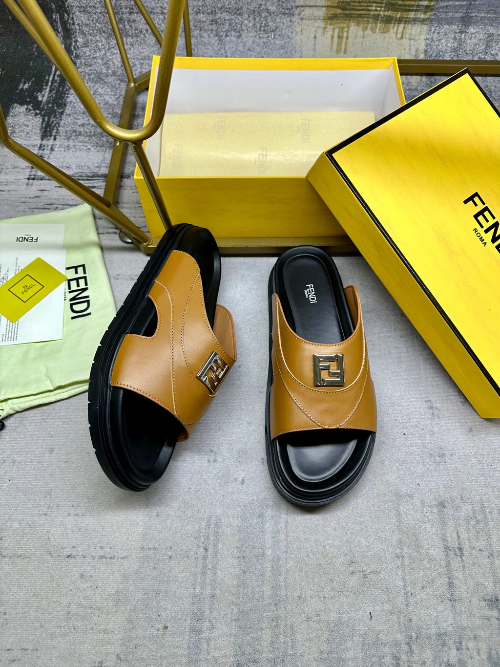 Fendi slide sandals, tan leather straps with gold logo buckle and chunky black soles.