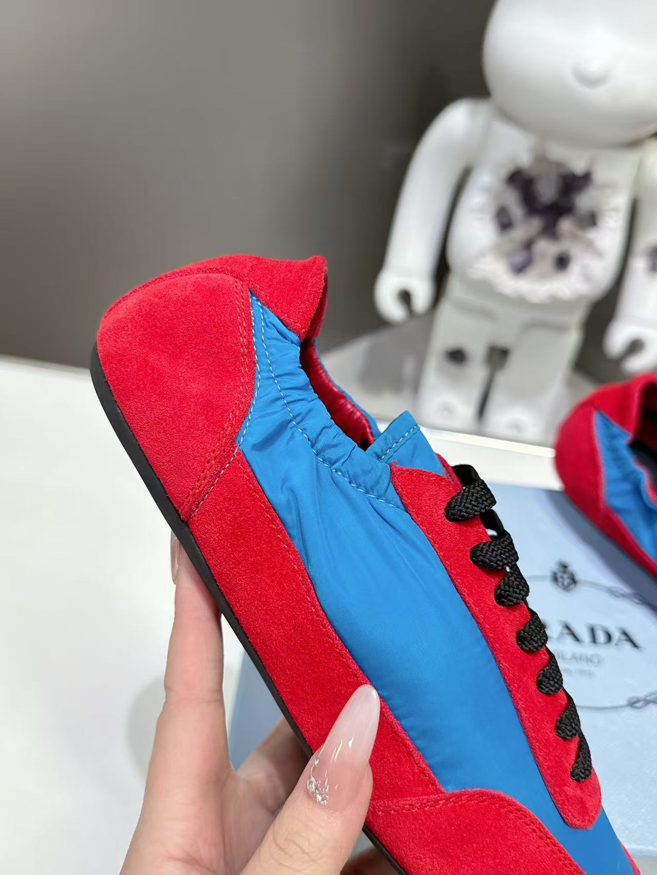 Prada unisex suede sneaker, red upper with blue panel and black laces, side view