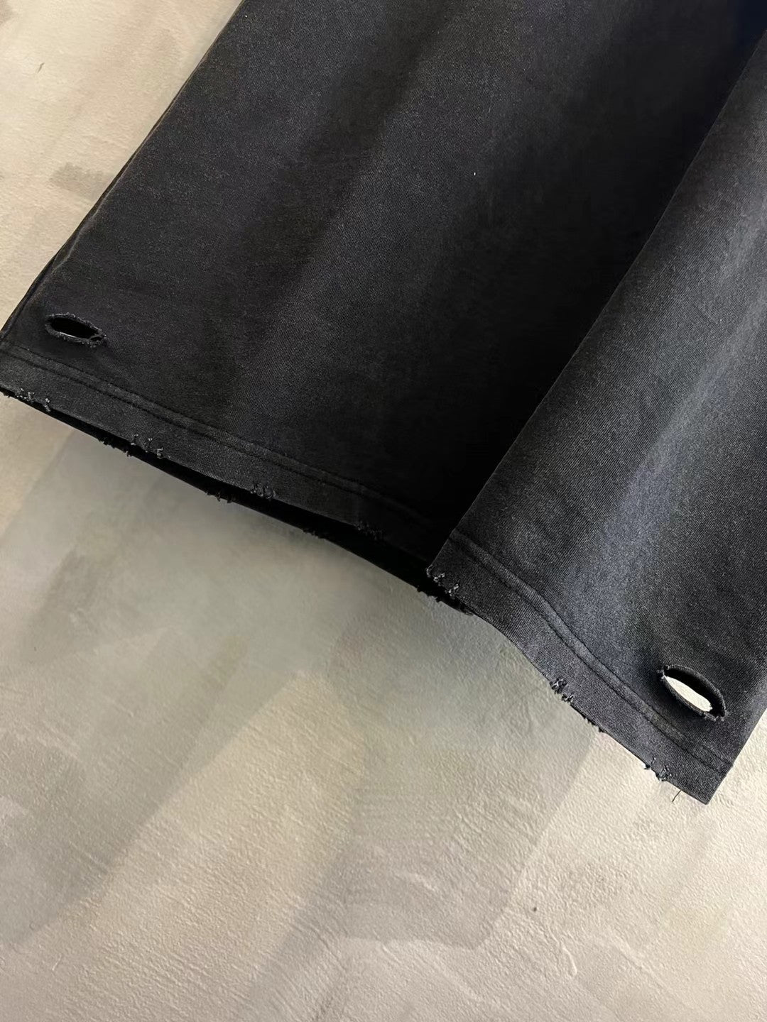 Black T-shirt cuff close-up with small ventilation slit and stitched hem detail