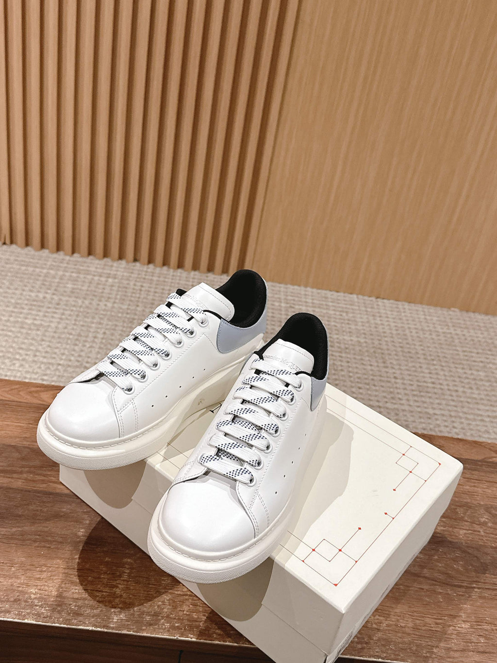 White leather lace-up sneakers with black heel lining, on box