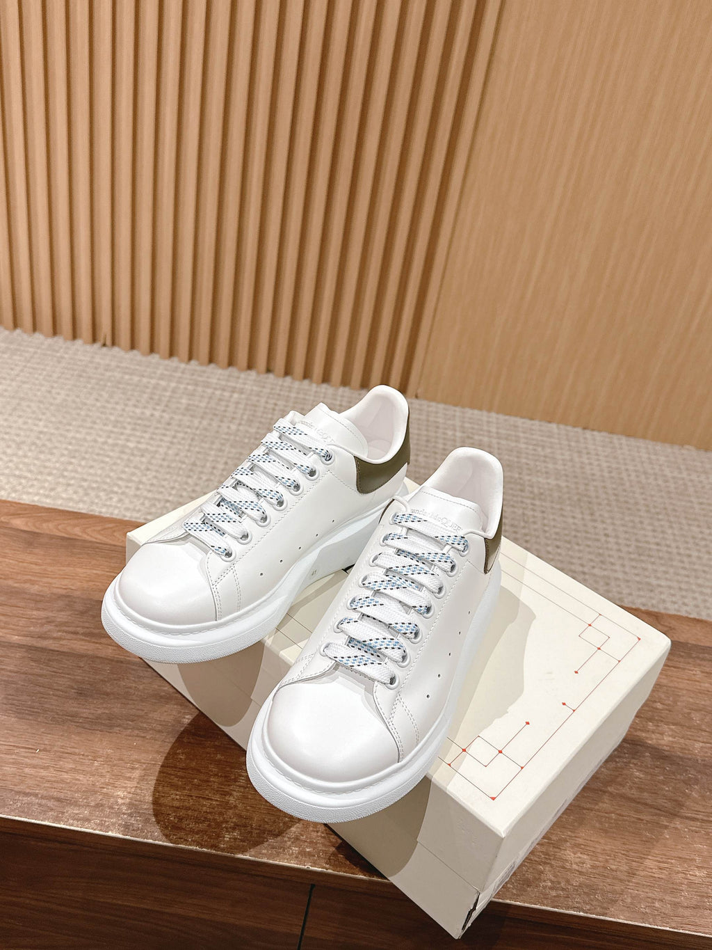 White leather sneakers with blue lace accents, shown with box