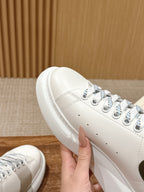 White leather sneaker side view with blue-accent laces and stitched details