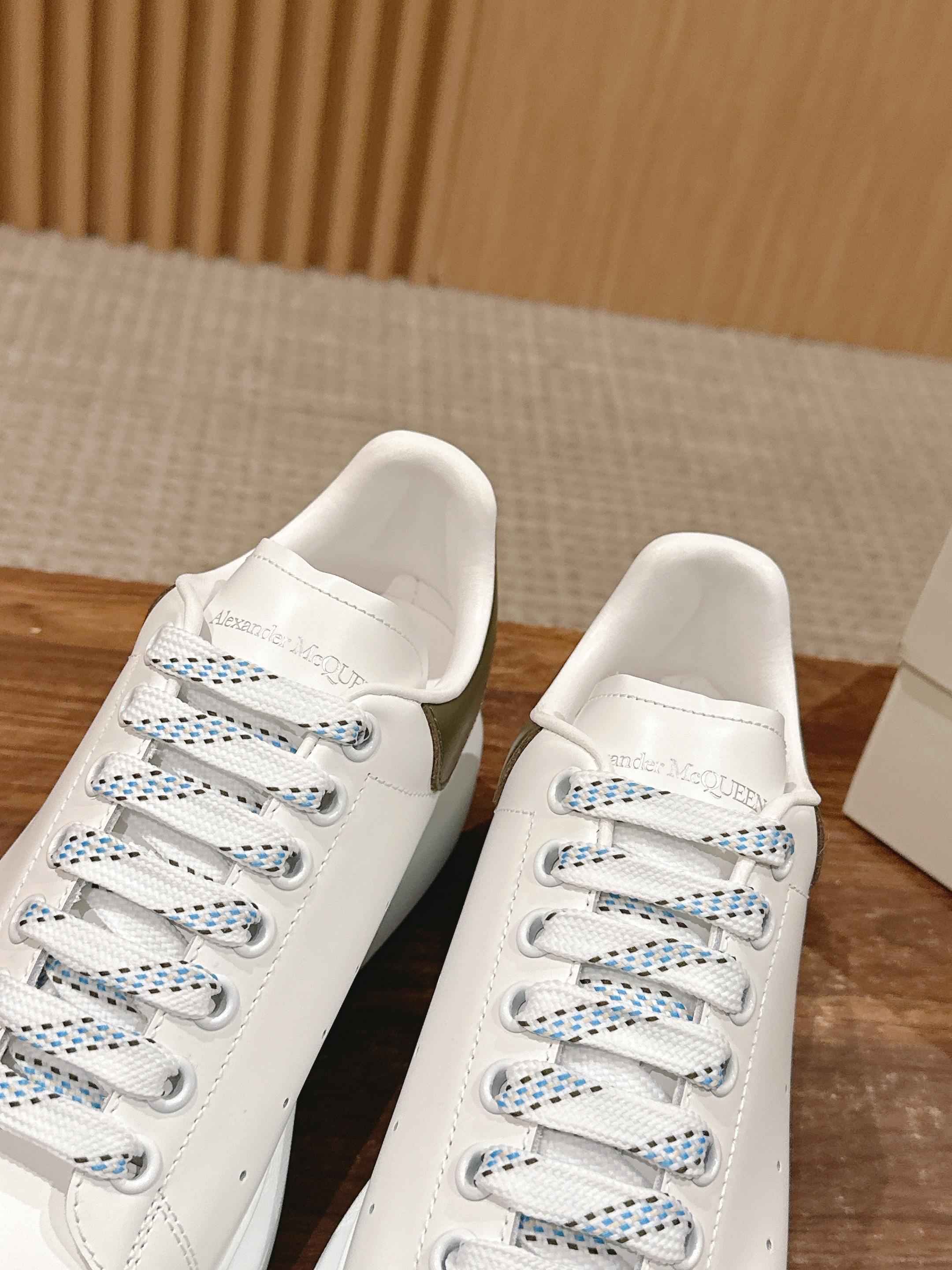 White leather sneakers with blue-striped laces and lace-up eyelets