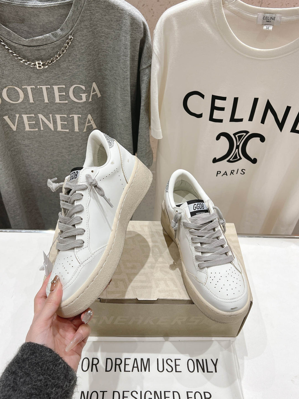 Golden Goose white sneaker with gray laces, one held up beside the pair