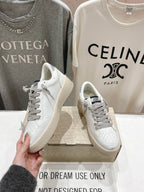 Golden Goose white sneaker with gray laces, one held up beside the pair