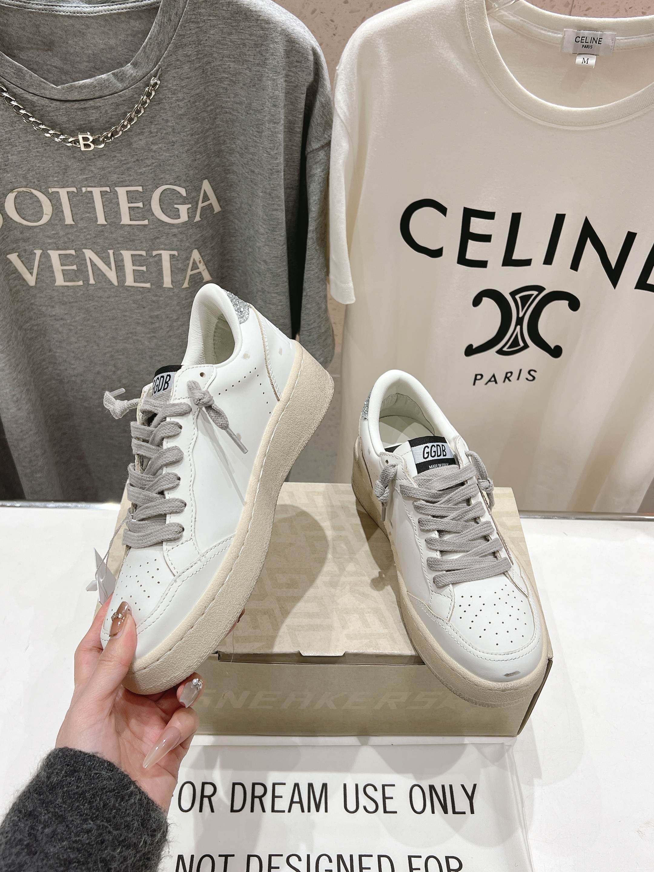 Golden Goose white sneaker with gray laces, one held up beside the pair