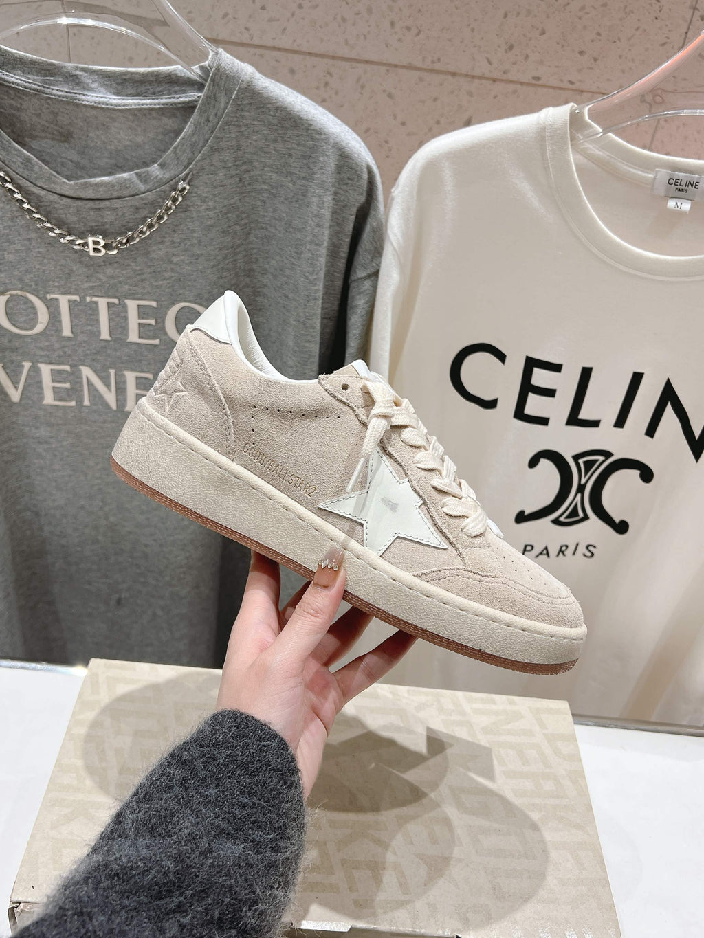 White low-top sneaker held up, lace-up with side star detail