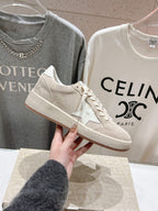 White low-top sneaker held up, lace-up with side star detail