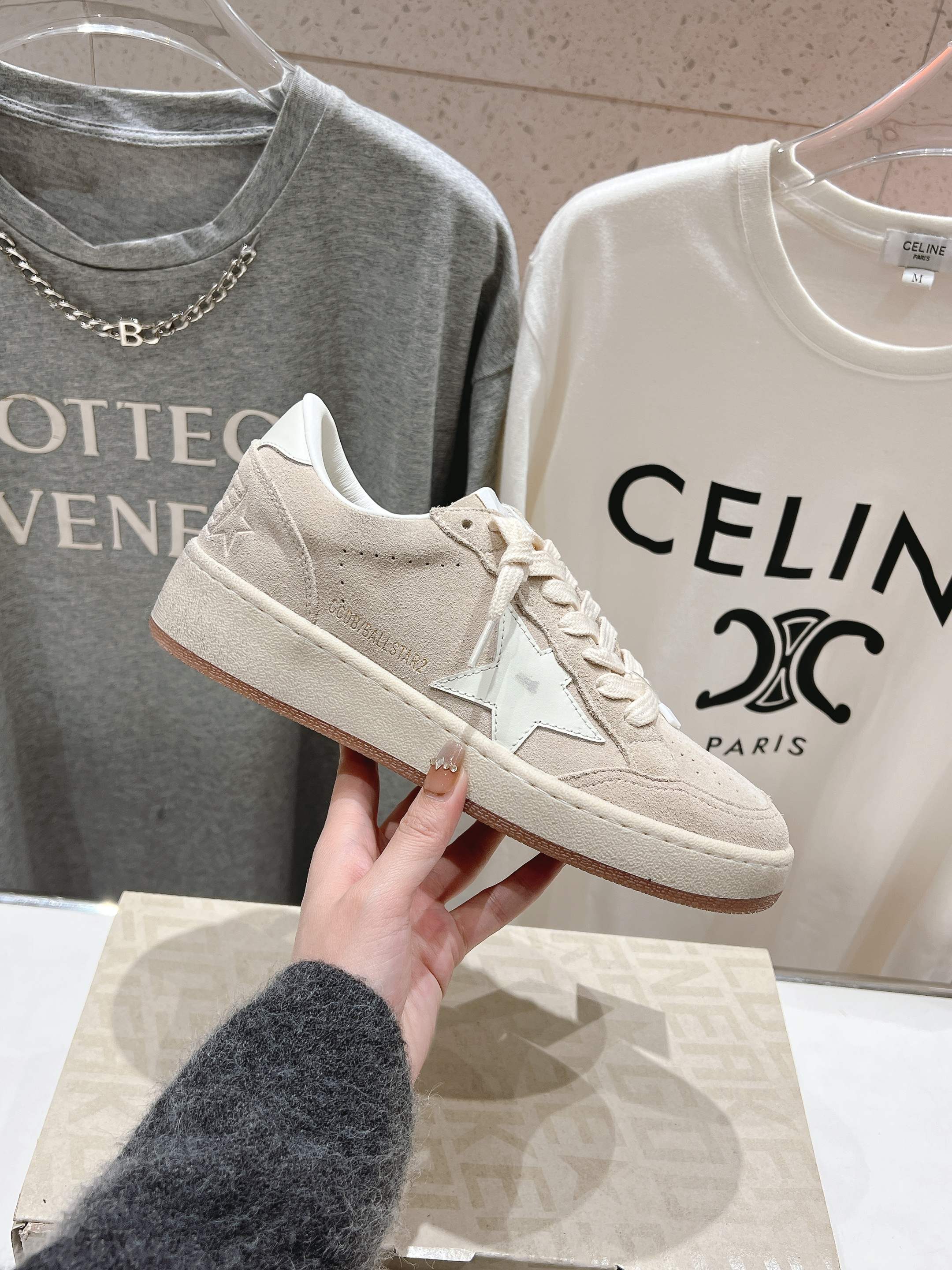White low-top sneaker held up, lace-up with side star detail
