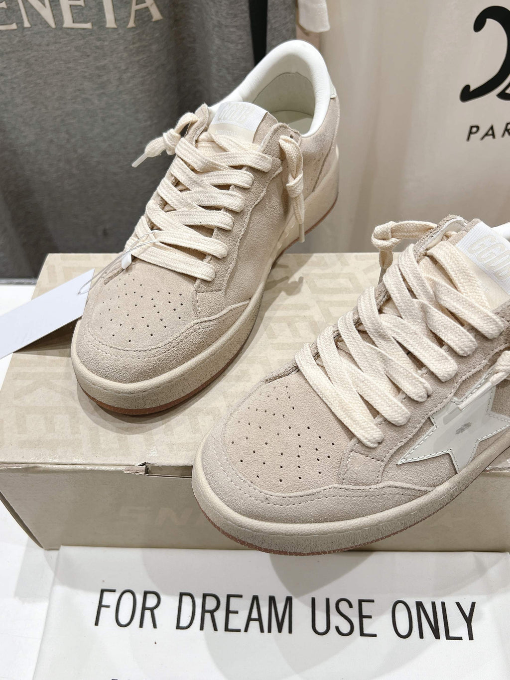 White lace-up sneakers, angled pair with side star detail on shoebox