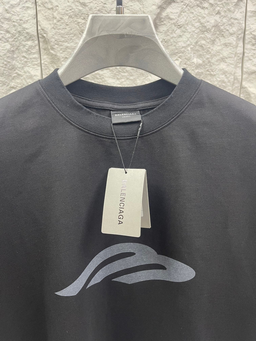 Dark graphic T-shirt close-up with hang tag and chest logo