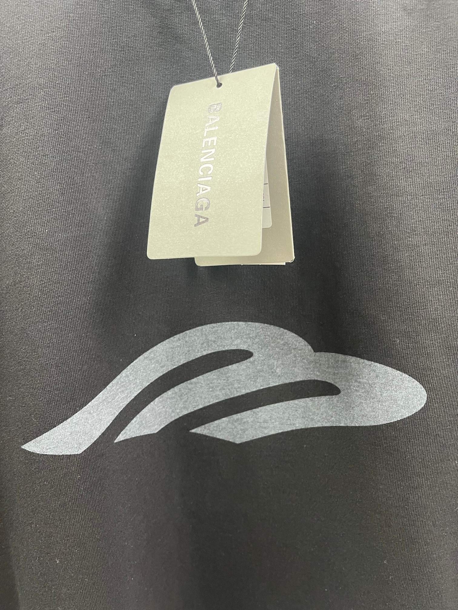 Dark T-shirt fabric close-up with hang tags and logo print