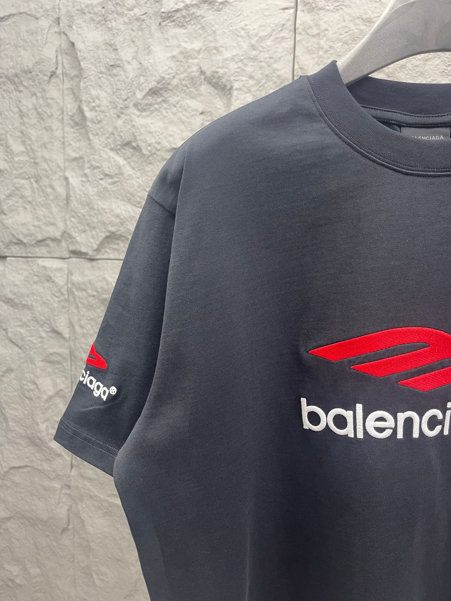 Balenciaga dark T-shirt with red logo graphic on sleeve and partial wordmark