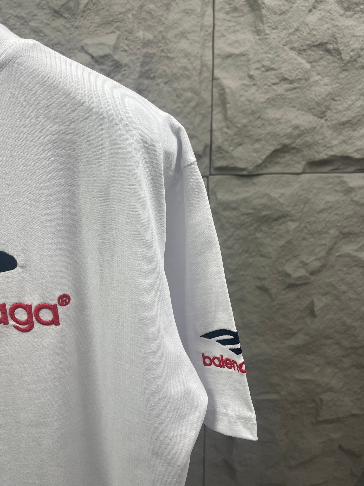 White Balenciaga T-shirt sleeve with red logo detail near cuff