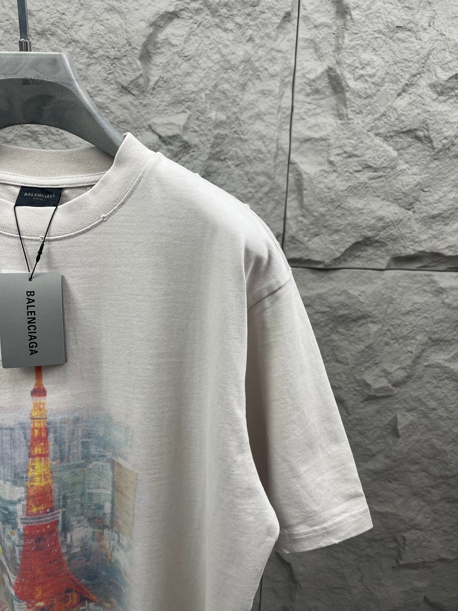 White T-shirt side view with partial Eiffel Tower print and Balenciaga hang tag
