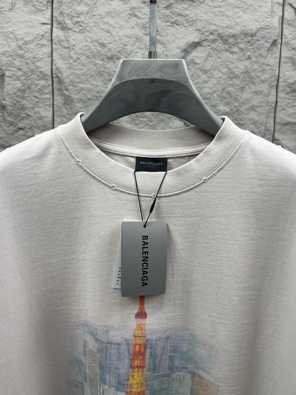 White T-shirt close-up with crew neck trim and Balenciaga hang tag