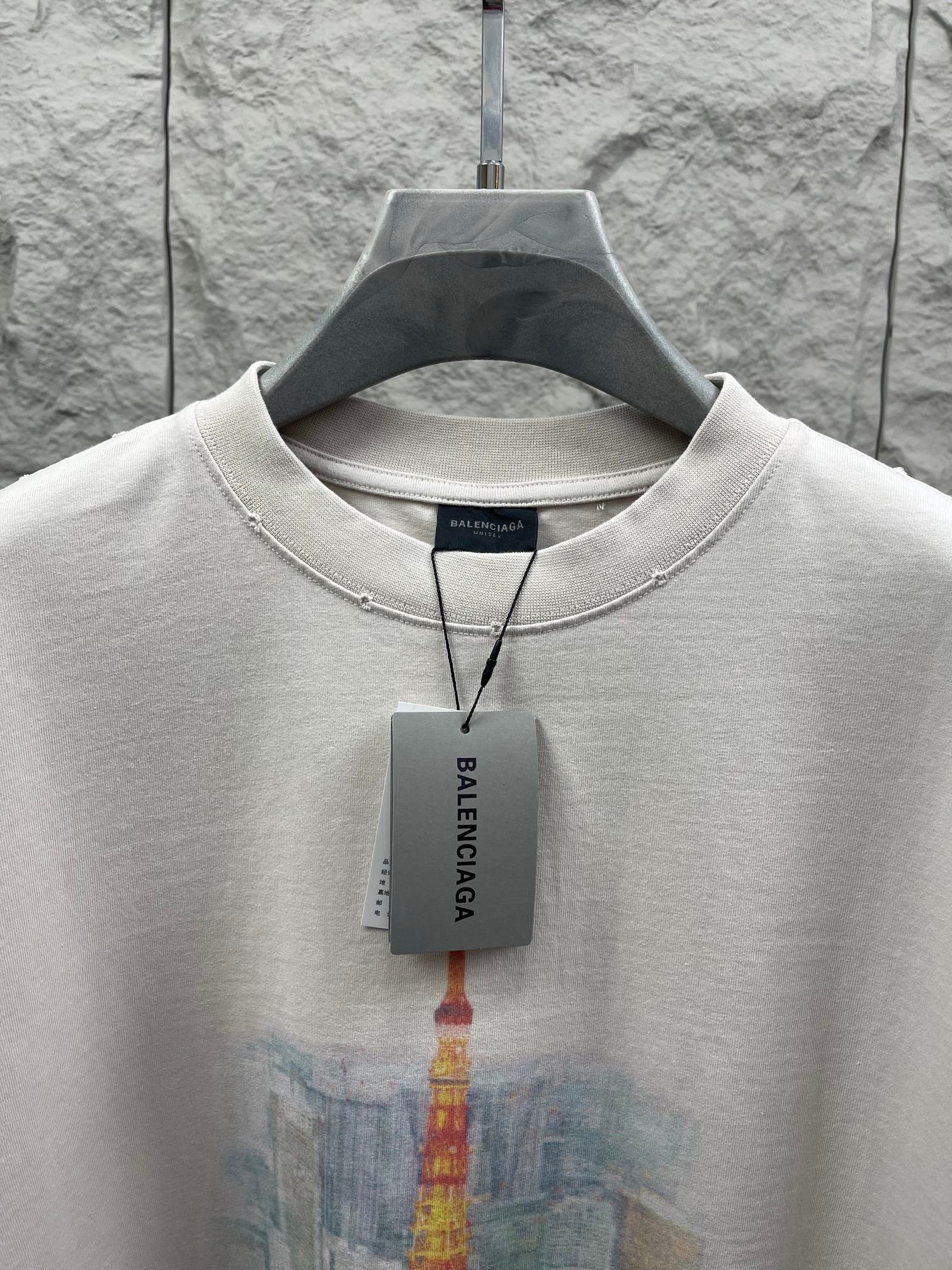 White T-shirt close-up with crew neck trim and Balenciaga hang tag