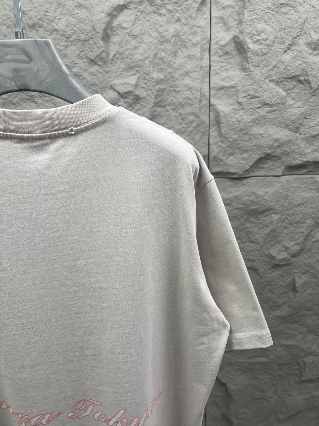 White T-shirt back view with red script logo near the lower back