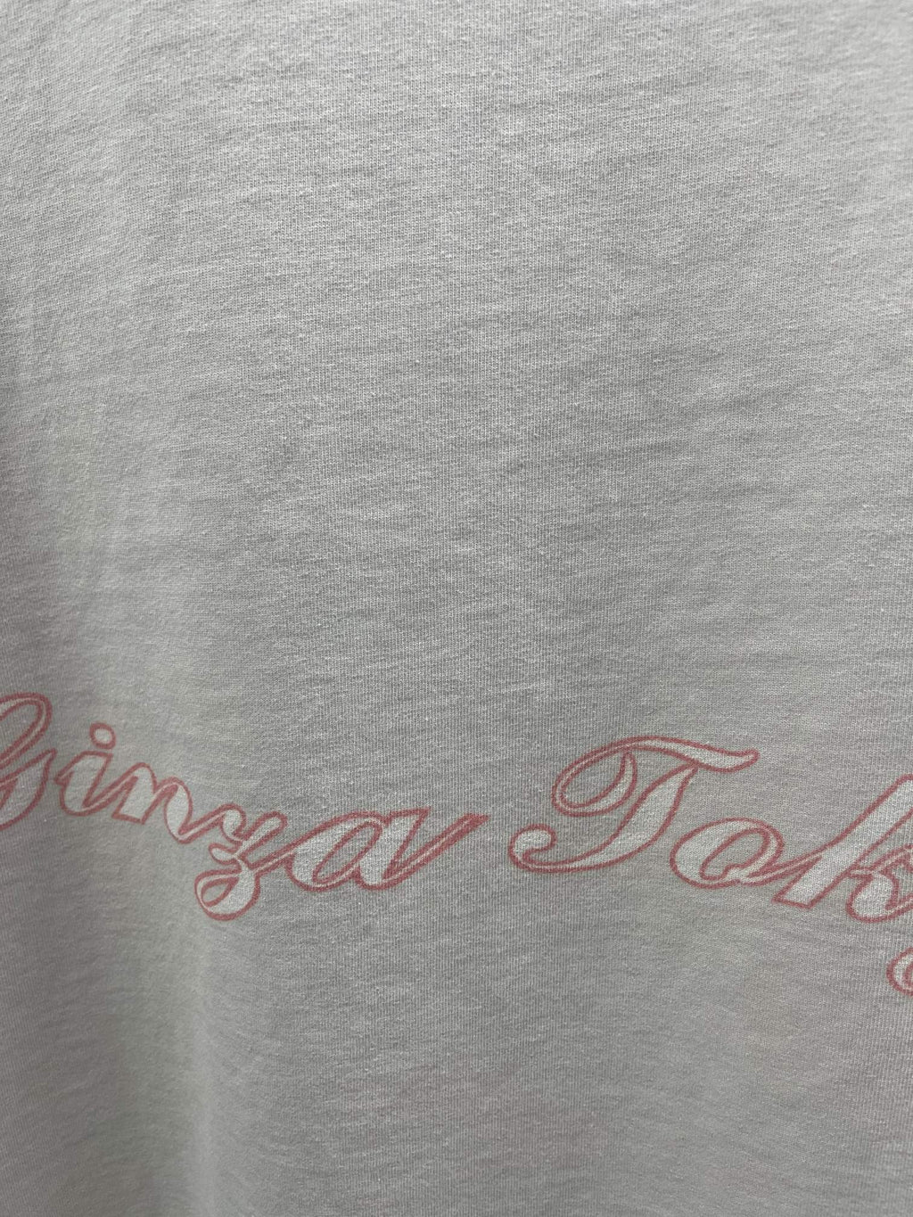 White T-shirt close-up with red scripted logo text