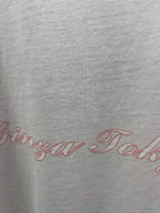 White T-shirt close-up with red scripted logo text