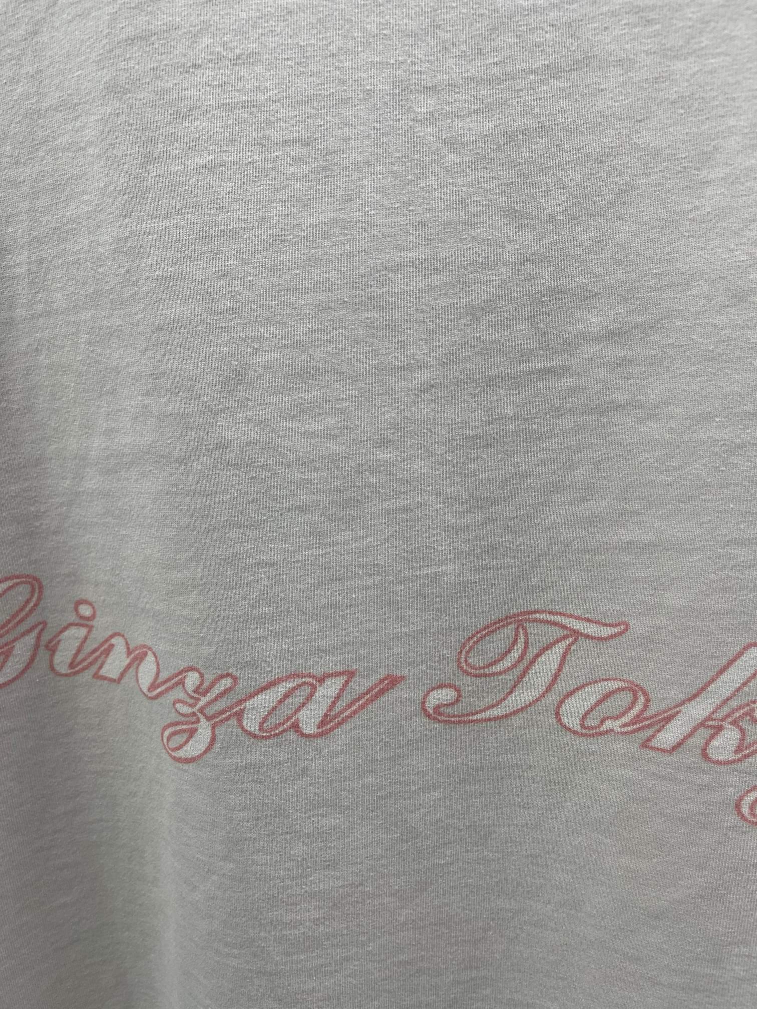 White T-shirt close-up with red scripted logo text