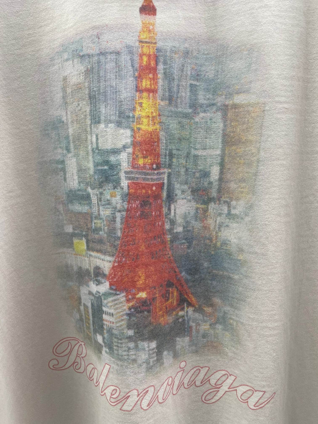 White T-shirt fabric close-up with red Eiffel Tower illustration and script logo