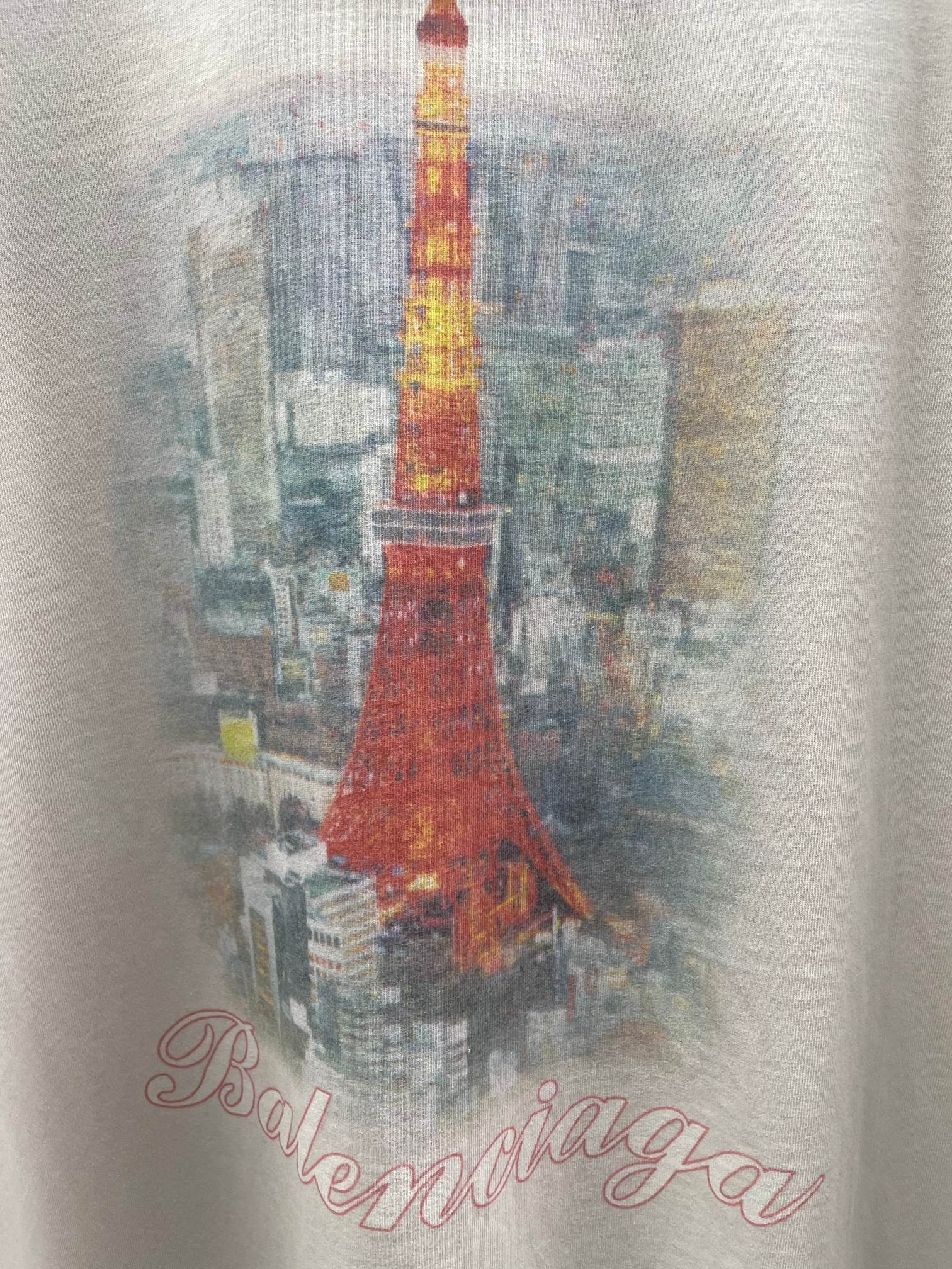 White T-shirt fabric close-up with red Eiffel Tower illustration and script logo