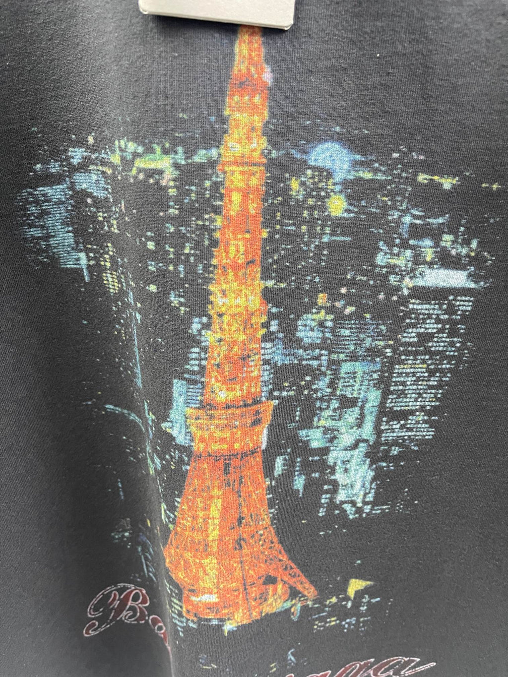 Close-up of dark gray T-shirt fabric with Eiffel Tower graphic in orange, yellow, and blue