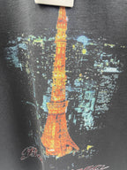 Close-up of dark gray T-shirt fabric with Eiffel Tower graphic in orange, yellow, and blue