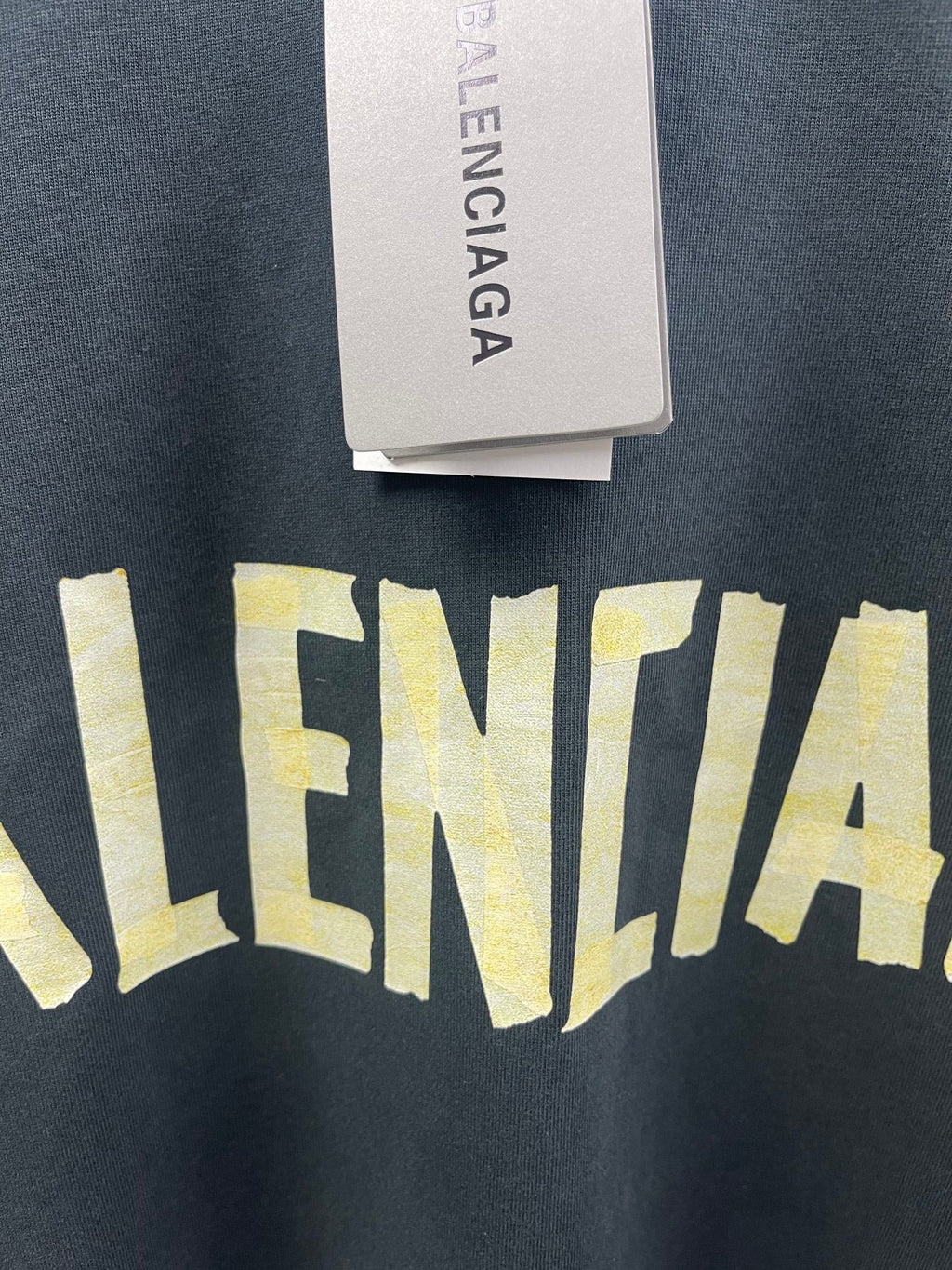 Dark T-shirt fabric with large yellow Balenciaga wordmark detail