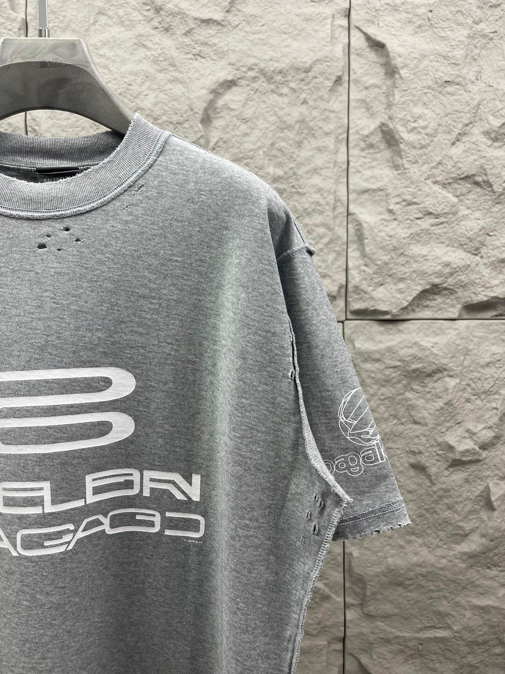 Grey T-shirt with logo graphic on sleeve and crew neck.