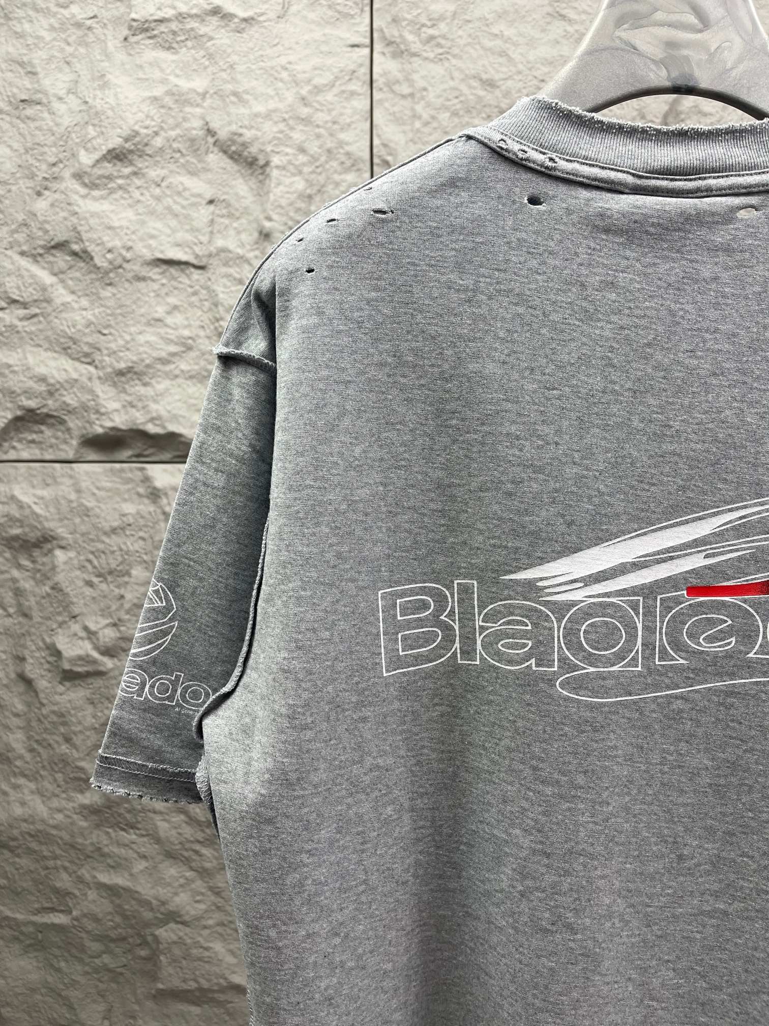 Grey T-shirt back with partial logo print and red detail on text.