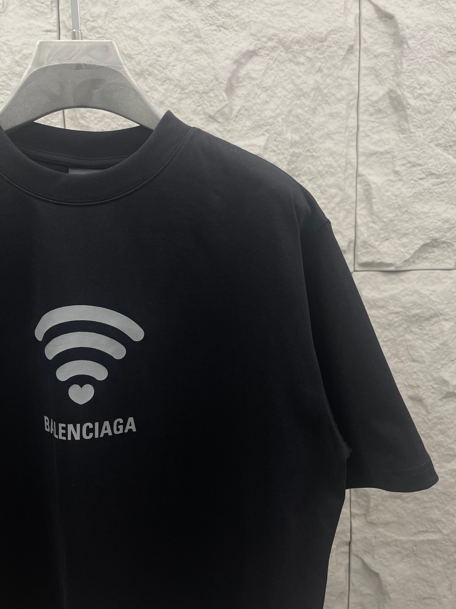 Balenciaga dark T-shirt sleeve and chest graphic with Wi‑Fi heart and logo
