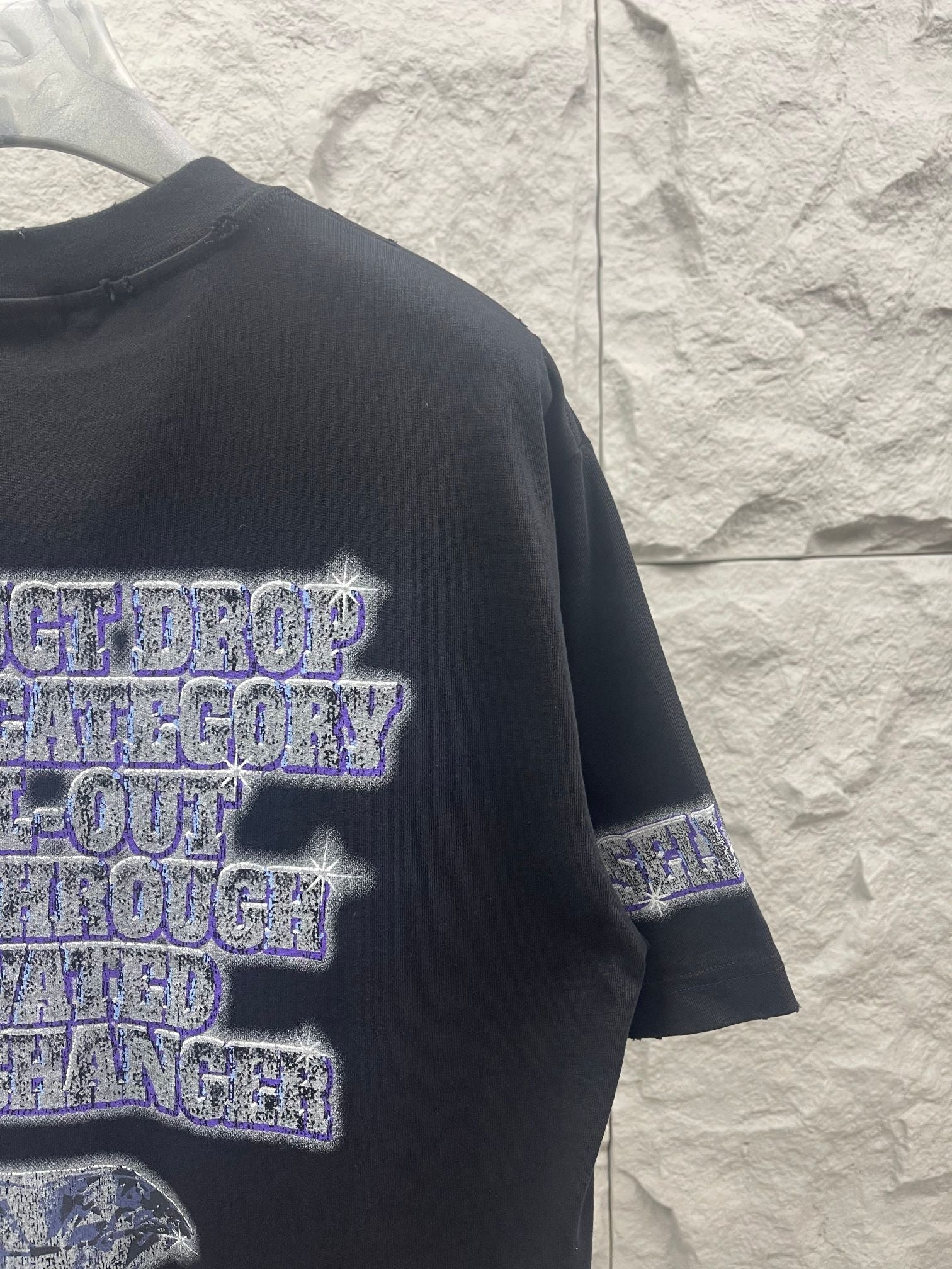 Balenciaga graphic T-shirt in dark color, side view showing layered text print