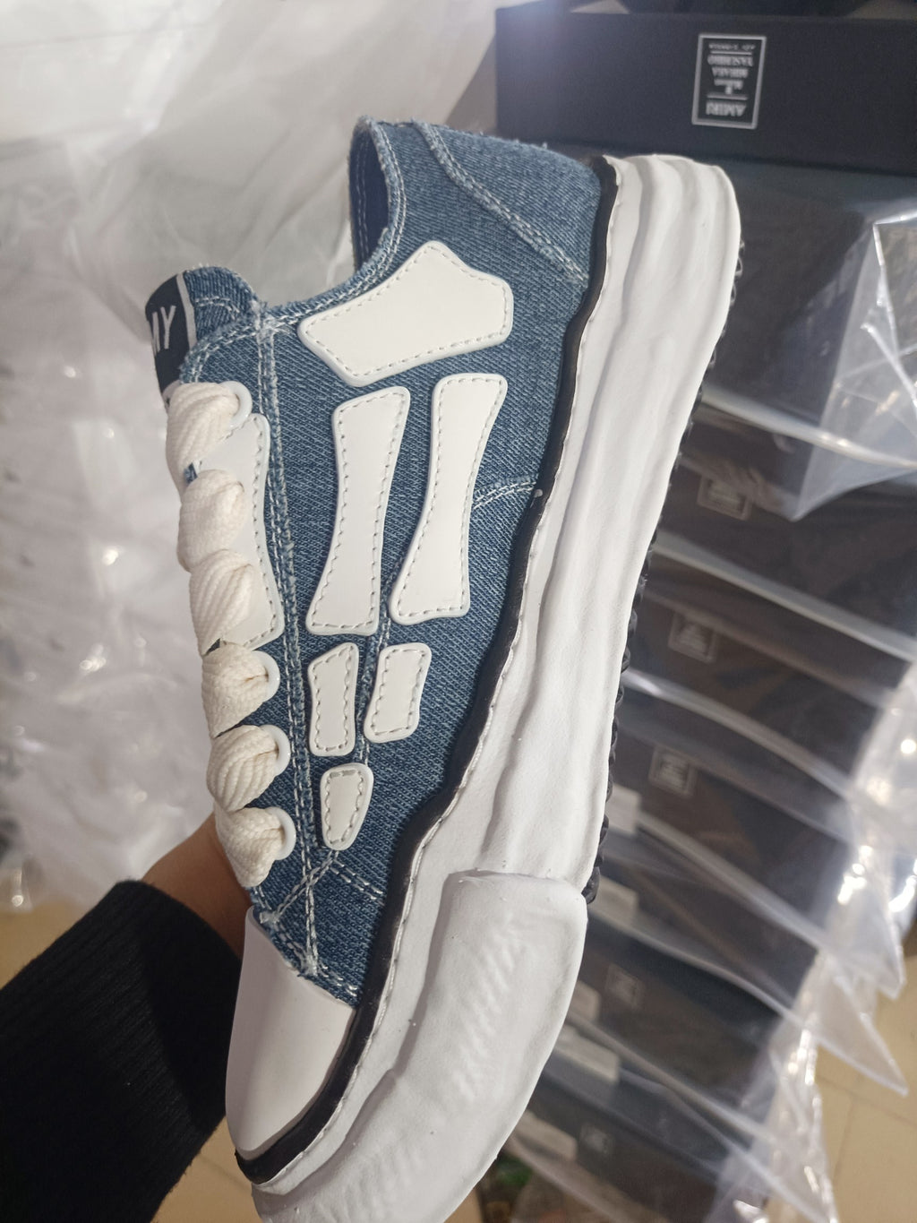 Denim low-top sneakers side view with white H-style overlays and cream laces
