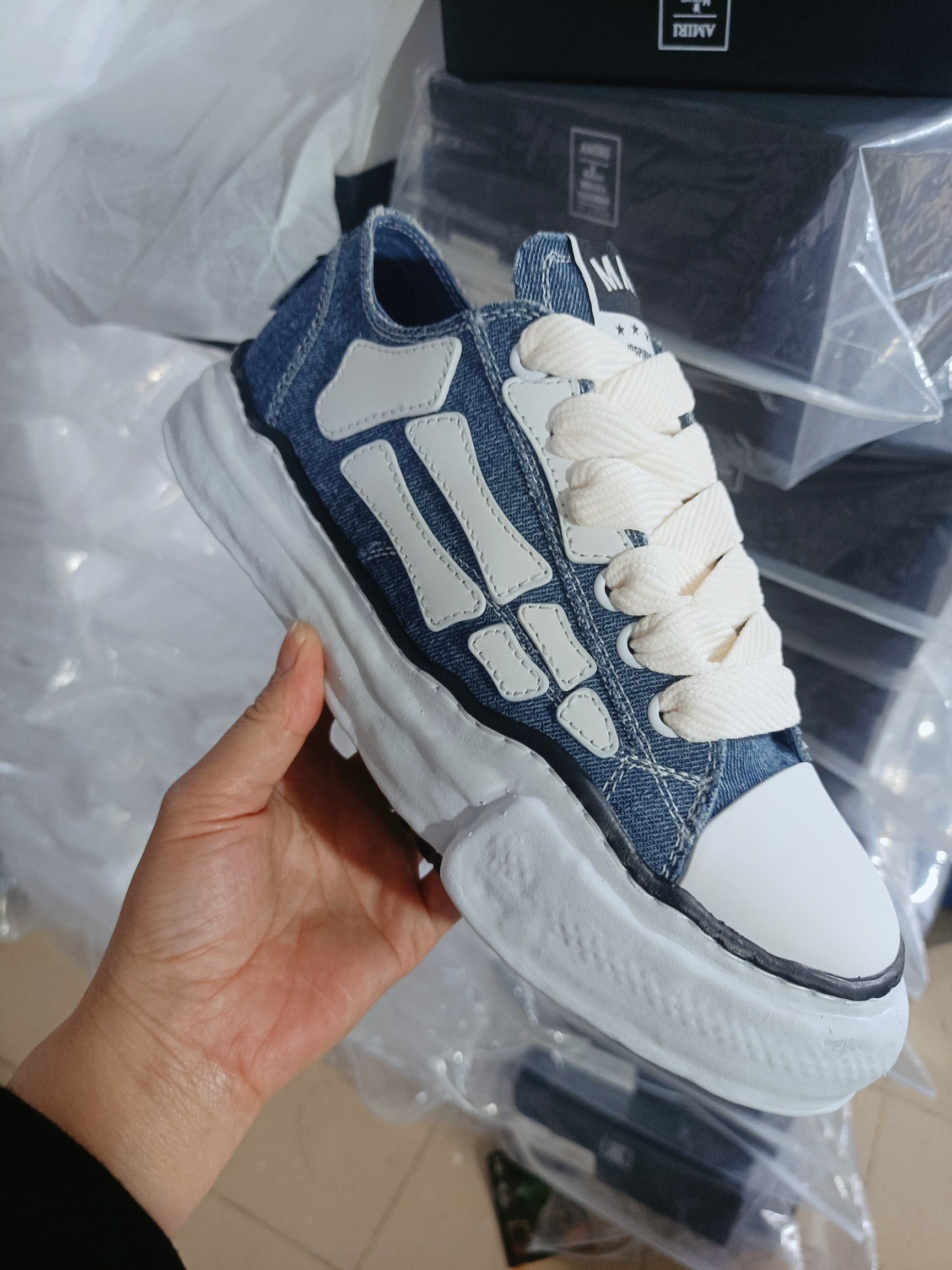 Denim low-top sneakers with white overlays, cream laces, thick rubber sole