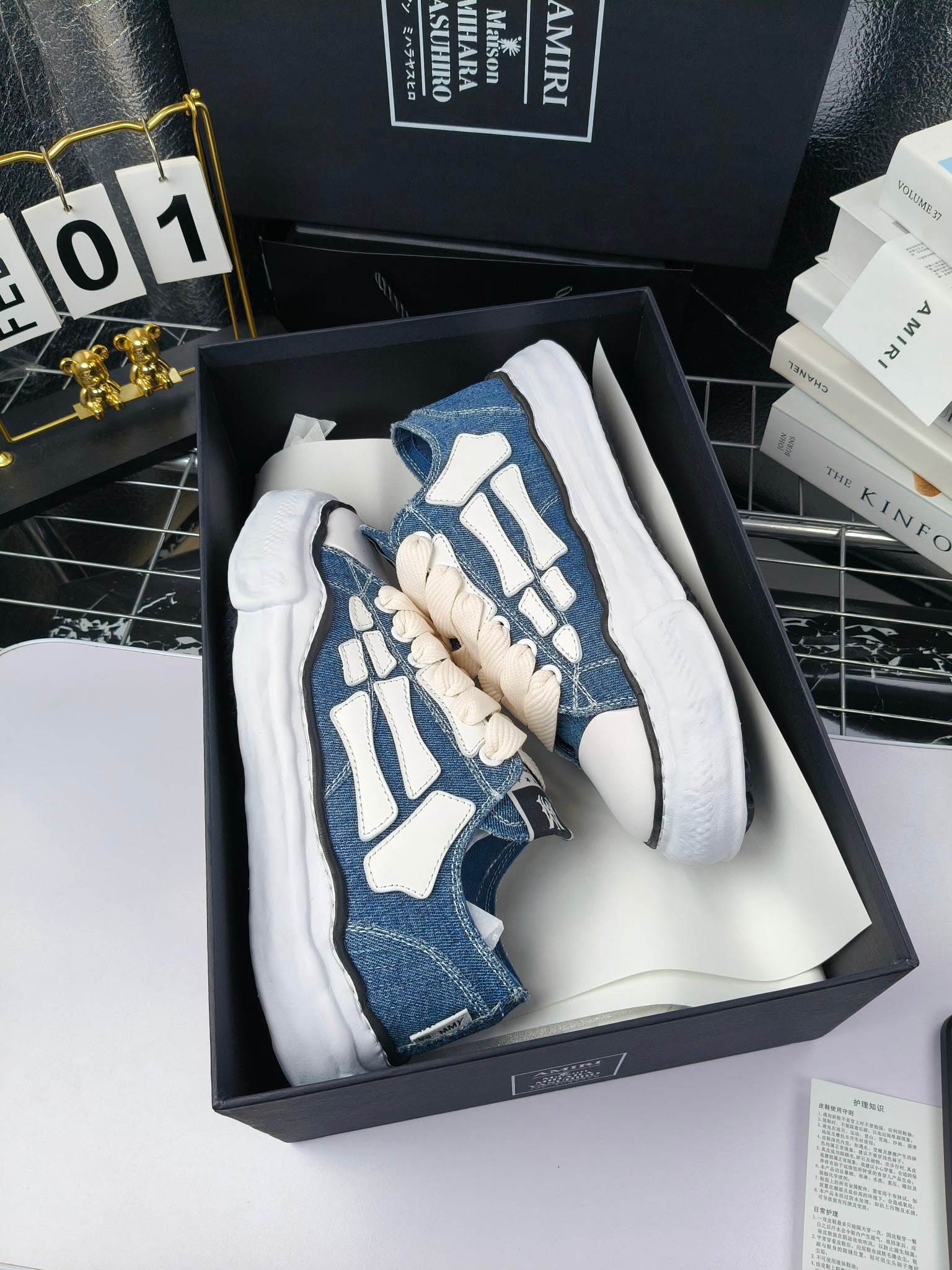 Blue denim low-top sneakers with white laces and white side accents, in open box